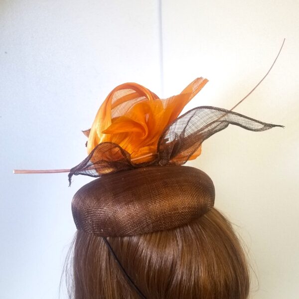 brown button hat with orange trim feather and leaf